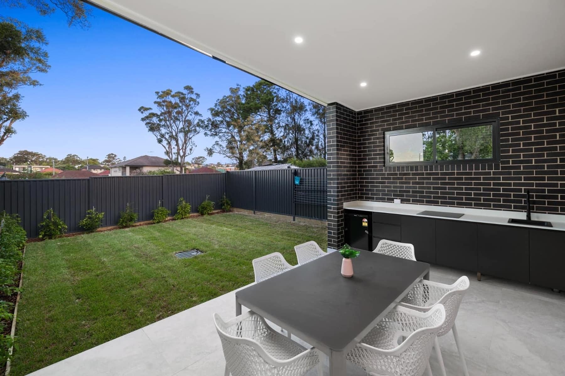 Twilight street view of the Cantrell Street duplex pair in Yagoona, with charcoal brick, white render and feature lighting