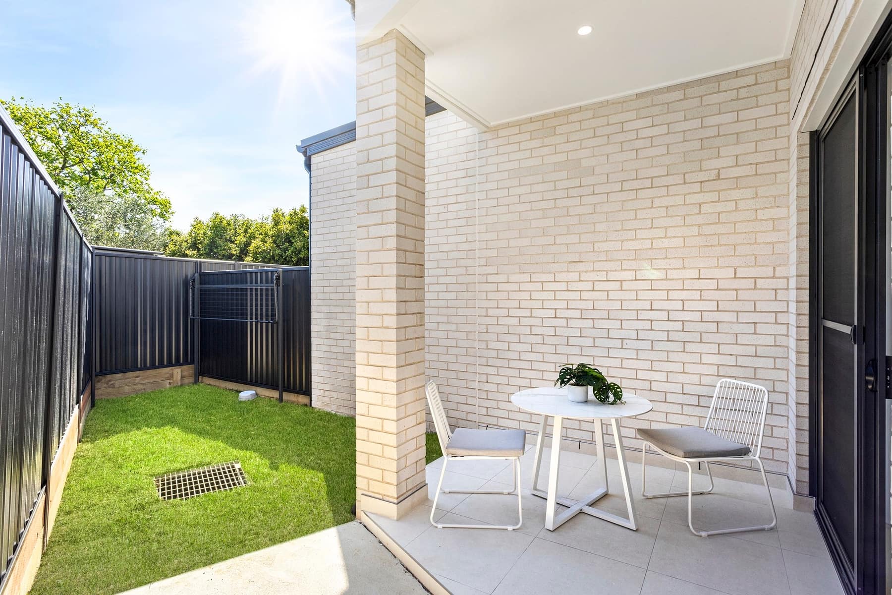 Street view of the four Stockton Avenue townhouses in Moorebank, with white render, balconies and dark garage doors